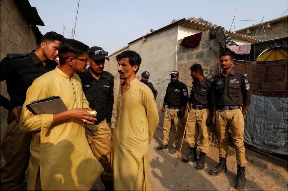A worker from the National Database and Registration Authority (NADRA), along with police officers, speaks to a resident while checking identity cards, during a door-to-door search and verification drive for undocumented Afghan nationals, in an Afghan camp on the outskirts of Karachi, Pakistan, November 21, 2023.