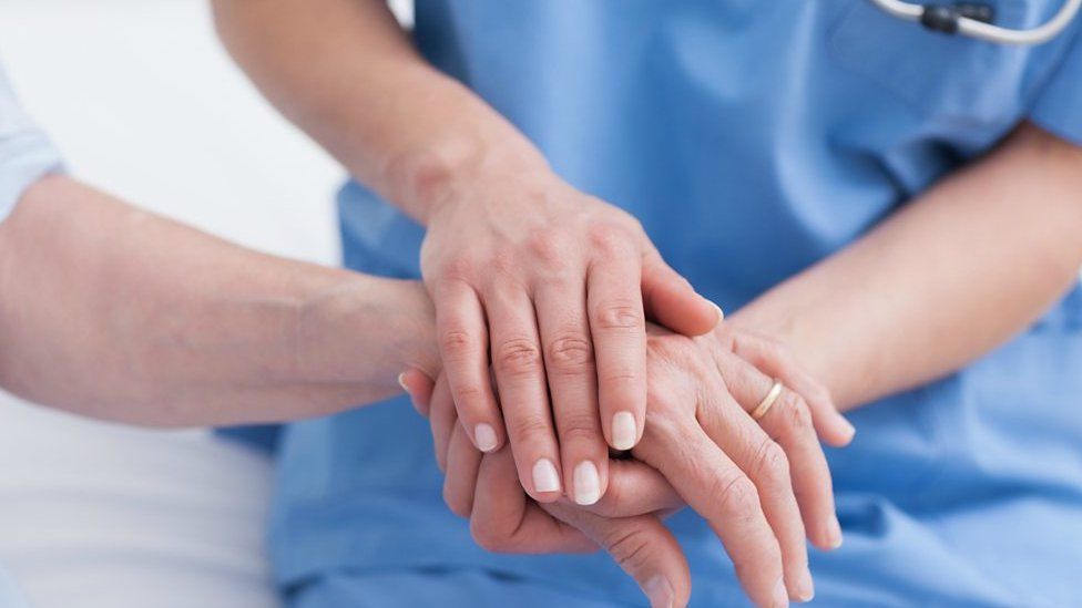 A nurse holding the hand of a patient