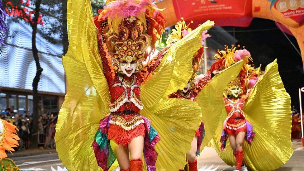 Wearing colourful outfits, several participants from the Granada Masskara Dance group take part in a parade in Hong Kong