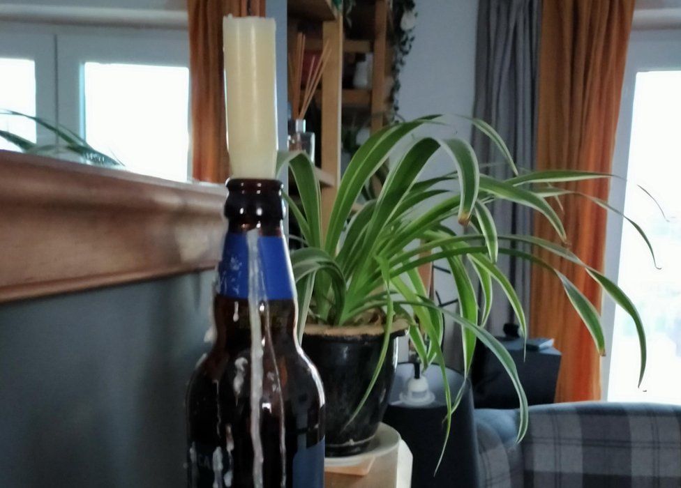 Candle in a bottle with plant in the background