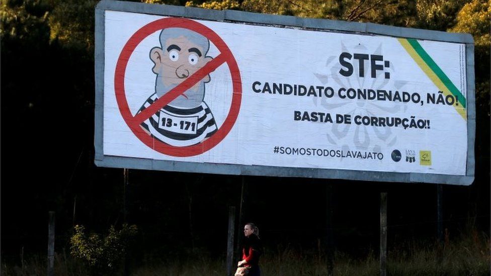 A woman walks past a billboard which reads: "No to convicted candidates! Stop corruption!".