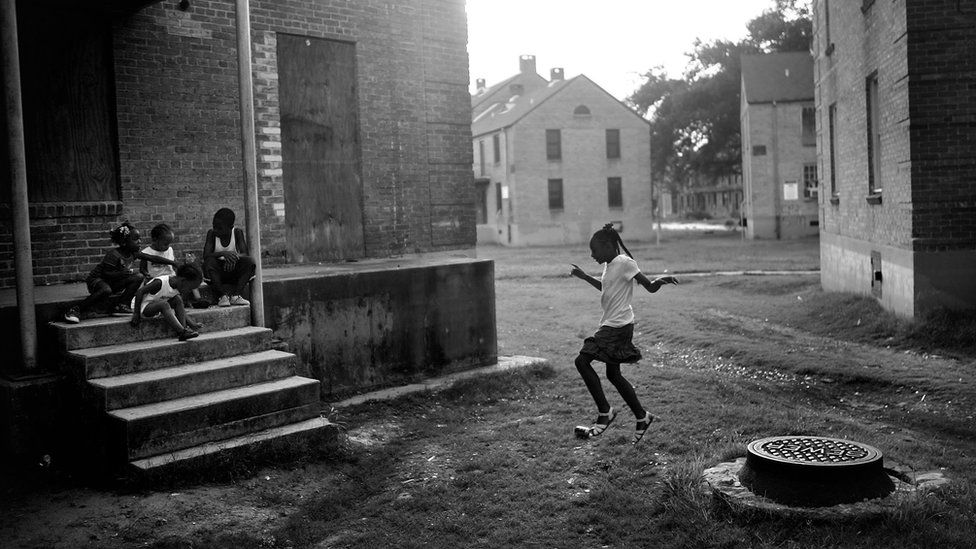 A girl jumps off a manhole cover as children gather in the B.W. Cooper housing projects June 2007 in New Orleans, Louisiana.