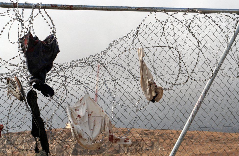 Blood-stained clothing hangs from the razor wire after a mass assault on the double fence into the Spanish enclave of Melilla from Morocco by African immigrants in October 2005