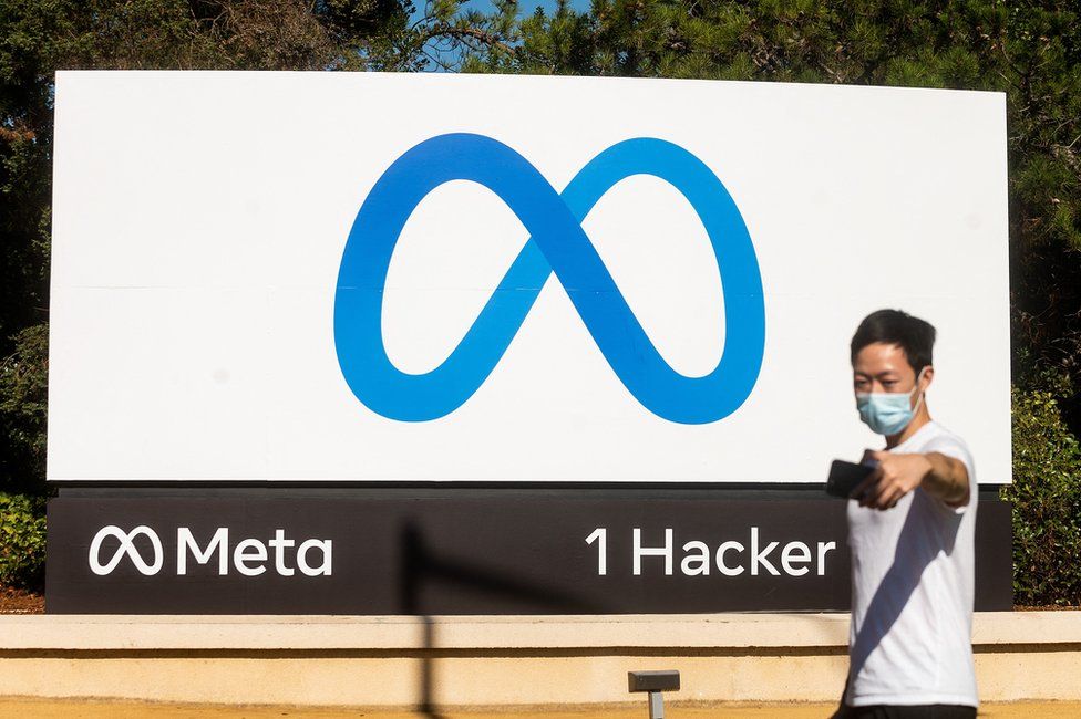 A person takes a selfie in front of a newly unveiled logo for Meta, the new name of Facebook's parent company, outside Meta's headquarters in Menlo Park, California, USA, on October 28, 2021.