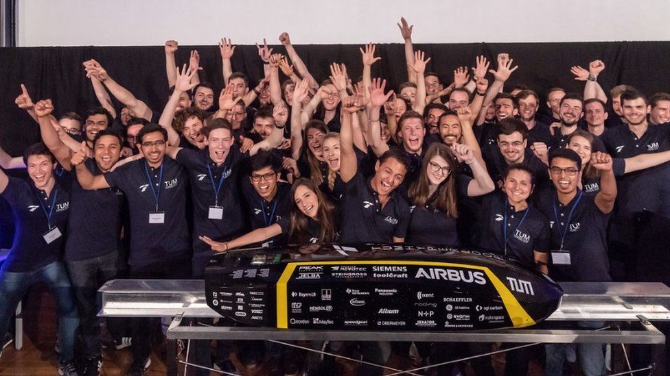 A Hyperloop test pod is surrounded by cheering students from the Munich University Team
