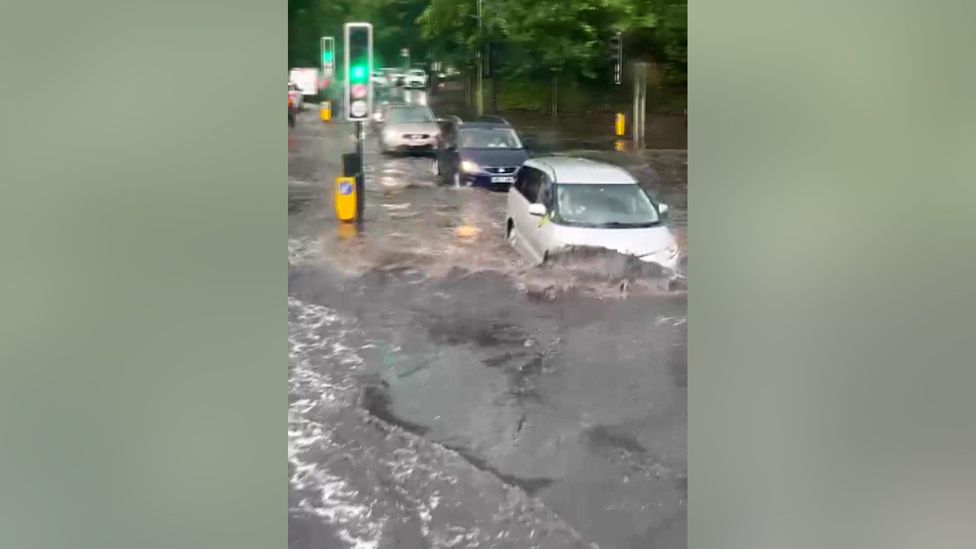 Wave forms as car pushes through flooding in London