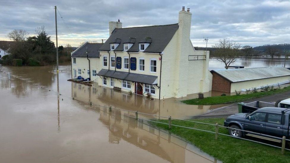 The Haw Bridge Inn exterior flooded with brown water up to the windows