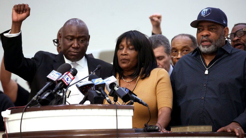 RowVaughn Wells is supported by civil rights attorney Ben Crump and her husband Rodney Wells while speaking to the media