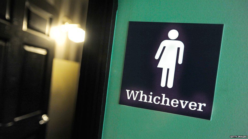 Дверь в ванную с нейтральной в гендерном отношении табличкой с надписью «Какой бы ни была» ||