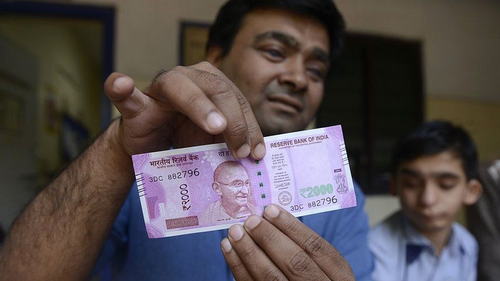 In this photograph taken on November 28, 2016, Indian visually impaired teacher from the Kendriya Vidhyalaya School, Dilipbhai Chauhan demonstrates how to identify a new 2000 rupee note at the Blind People's Association in Ahmedabad. The new 500 and 2000 rupee notes carry improved identification marks, including angular bleed lines - elevated markings - on the left and right of the notes, so that visually impaired people can identify the denomination.