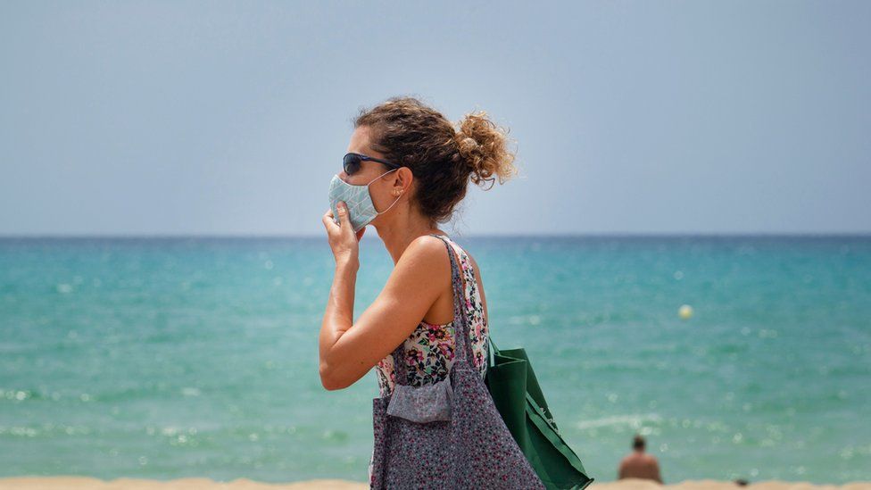 A woman adjusts her mask at Palma Beach in Palma de Mallorca