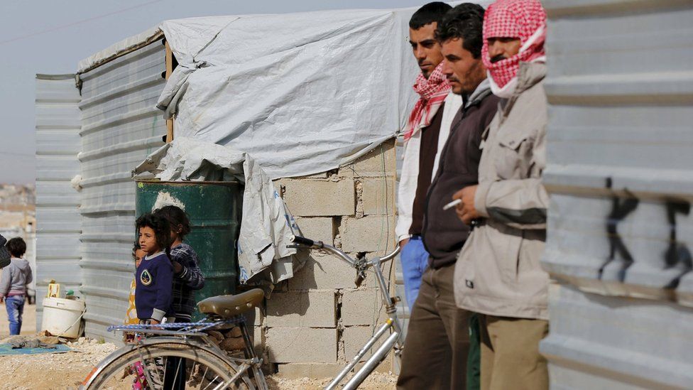 Syrian refugees watch as UK Foreign Secretary Philip Hammond visits Zaatari refugee camp in the Jordanian city of Mafraq (1 February 2015)