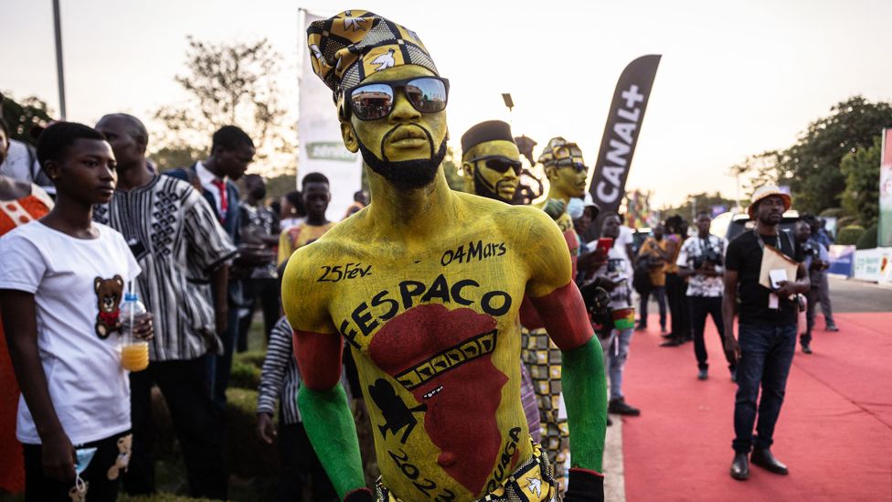 A man with body paint advertising Fespaco waits on the edges of the red carpet a the film festival's opening ceremony in Ouagadougou, Burkina Faso - Saturday 25 February 2023