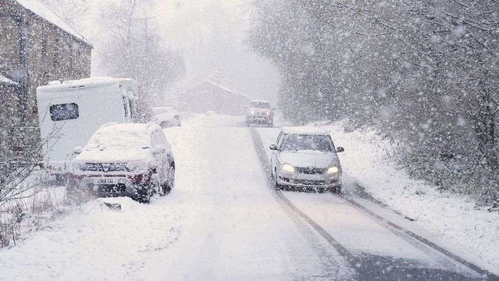 Cars drive through the snow in Gunnerside, North Yorkshire, on Sunday