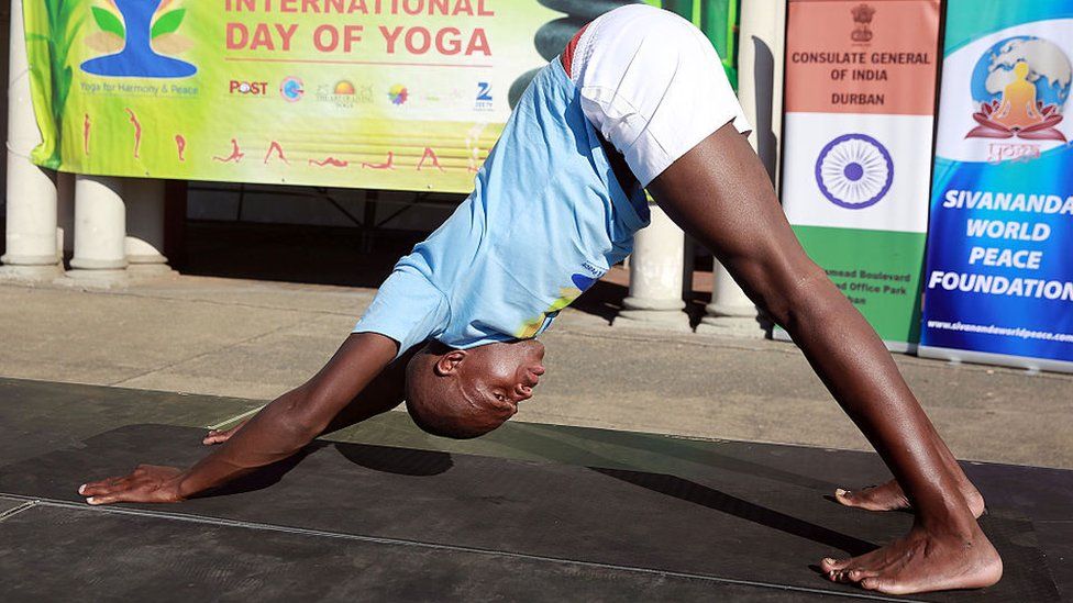 Man bends over making a triangle shape with his hands in front of him on a yoga mat