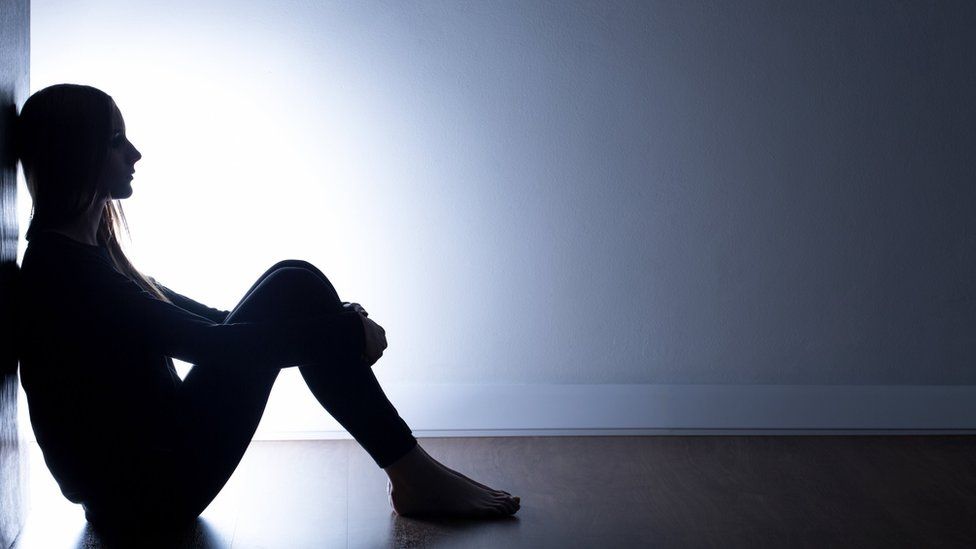 Depressed woman sat in dark
