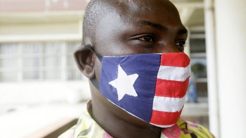 A man wears a mask decorated in the colour and pattern on Liberia's national flag on 27 April.