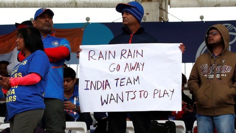 An India fan holds a sign saying 'Rain rain go away India team wants to play'