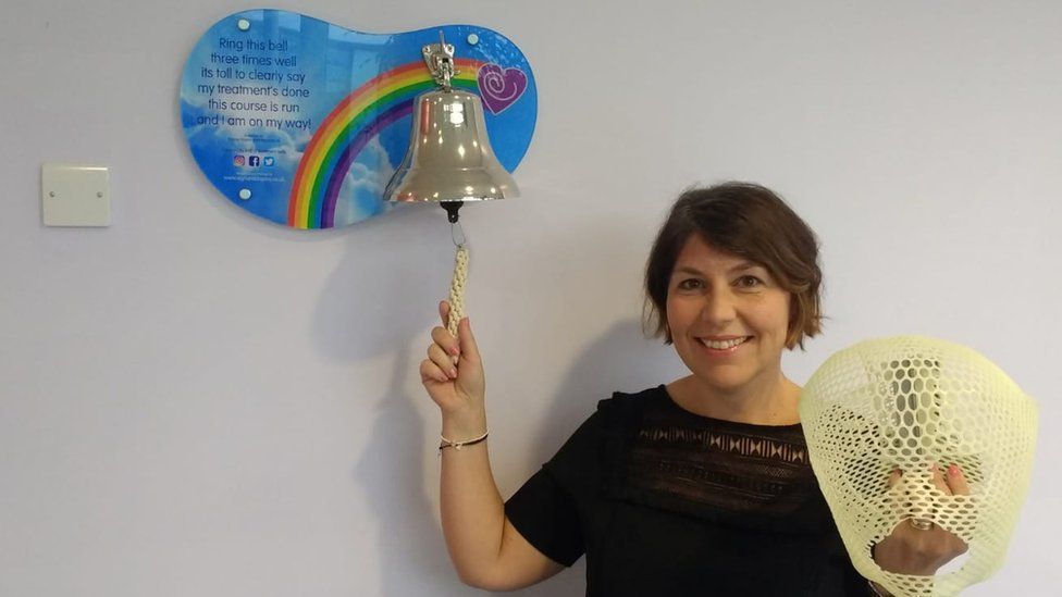 A woman ringing a bell at the end of cancer treatment