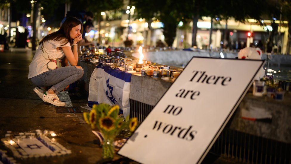 A young women kneels at a vigil site for hostages in Tel Aviv