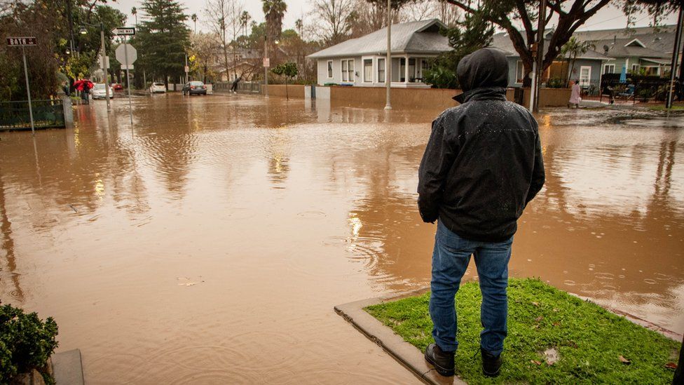 A man looks at the flooded intersection in Santa Barbara, California