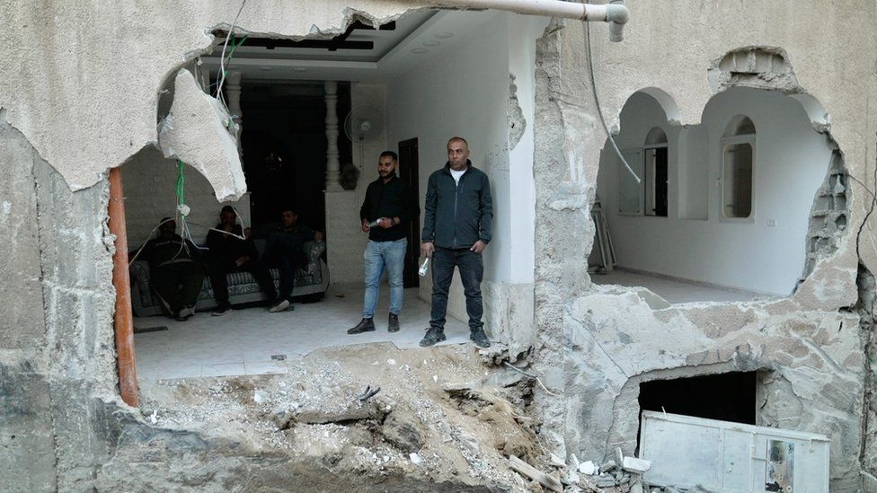 Palestinians stand in a damaged building in Jenin, in the occupied West Bank, following an Israeli military raid (29 November 2023)