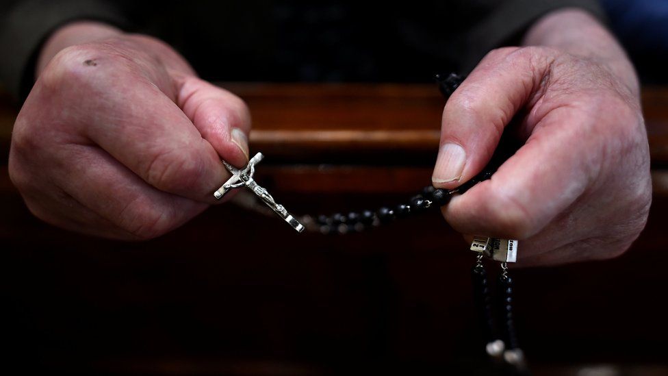 The hands of a worshipper are seen holding rosary beads in a church in Muckno, Ireland (20 June 2017)