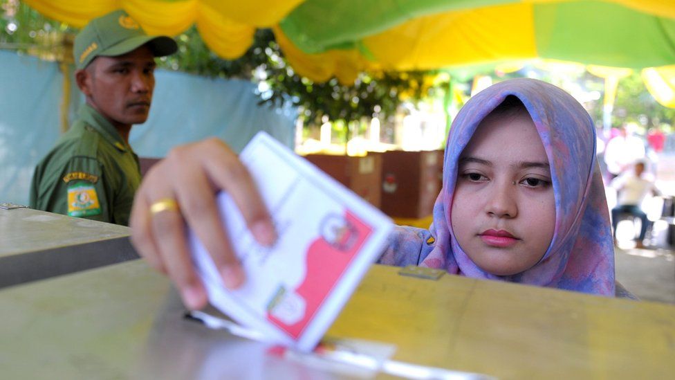 An Indonesian woman casts her vote in local elections at a polling station in Banda Aceh
