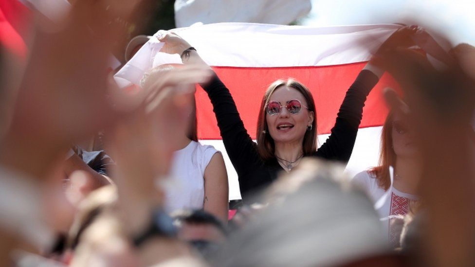 Svetlana Tikhanovskaya holds a flag aloft at a rally