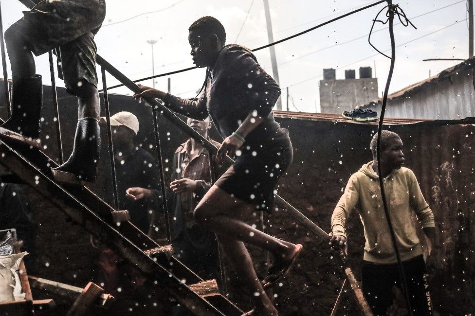 Residents climb to the rooftop to help put out a fire that razed twelve homes in Bombolulu, Kibera