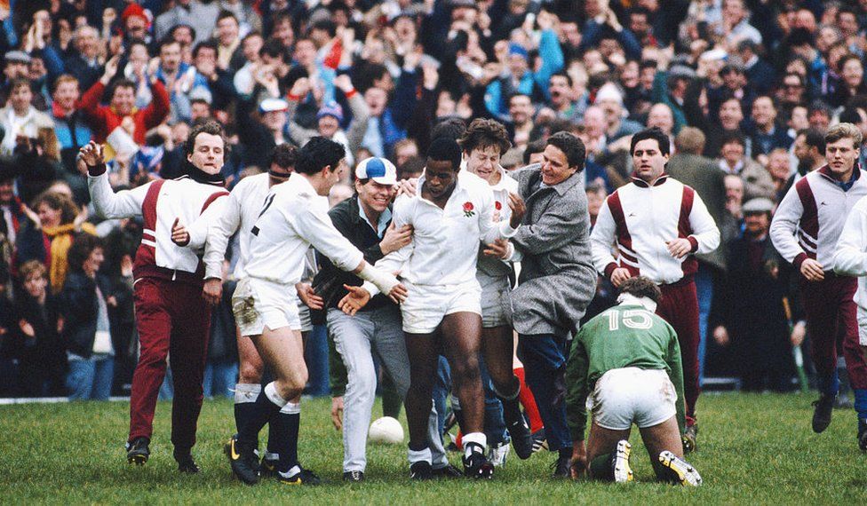 England wing Chris Oti (c) is congratulated by captain Will Carling (l) and spectators after scoring three trys in a 35-3 win over Ireland in the Five Nations match at Twickenham on March 19, 1988 in London, England.