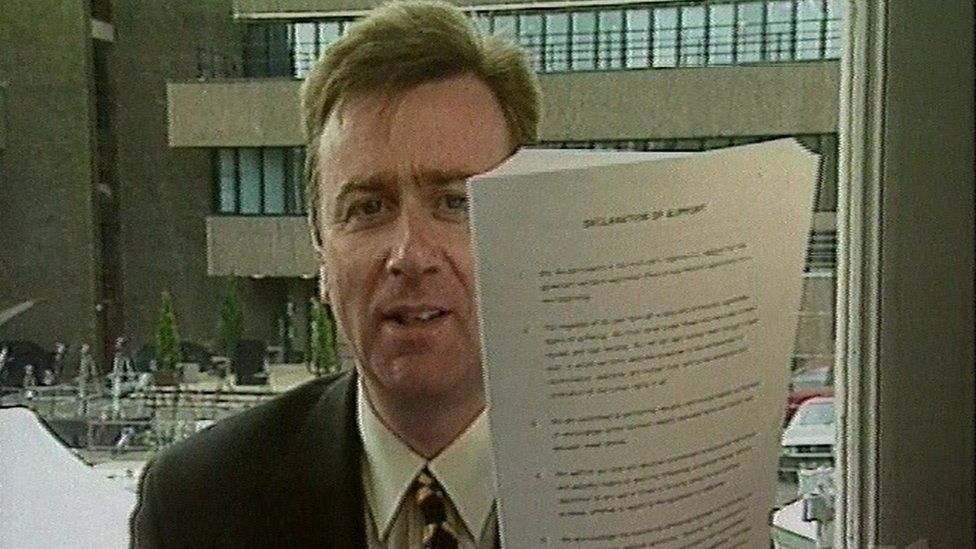 Stephen Grimason holding a copy of the Good Friday Agreement in April 1998