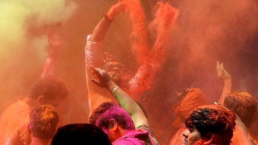Revellers smeared in coloured powder dance during the Holi celebrations, the Hindu spring festival of colours, in Hyderabad on March 17, 2022.