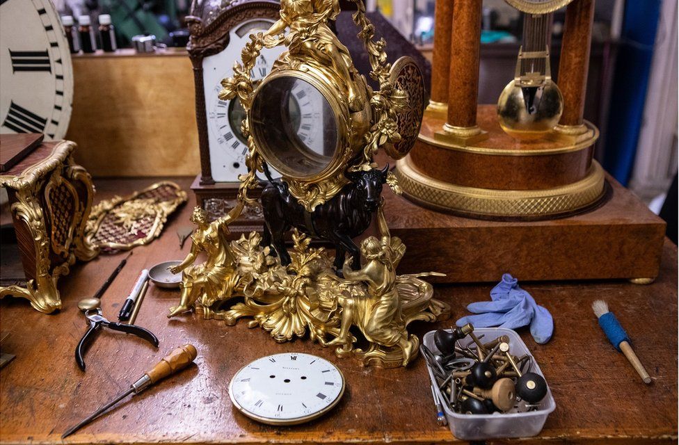 A clock case on a work bench surrounded by tools