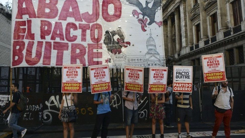 Demonstrators hold signs reading "Down with the Vulture"s Deal" while Argentine senators debate a deal to repay disgruntled creditors, as the government seeks to end a 15-year battle in the US courts over a catastrophic debt default, outside the National Congress in Buenos Aires, on March 30, 2016