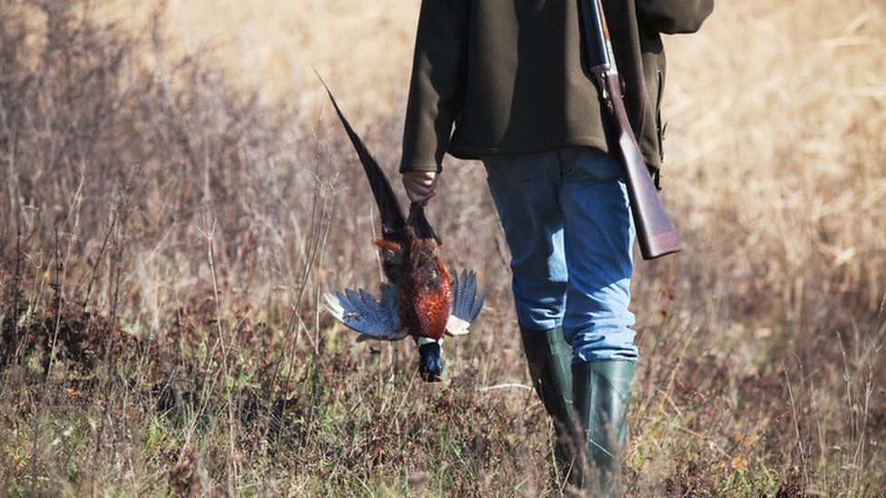 A hunter carrying a pheasant