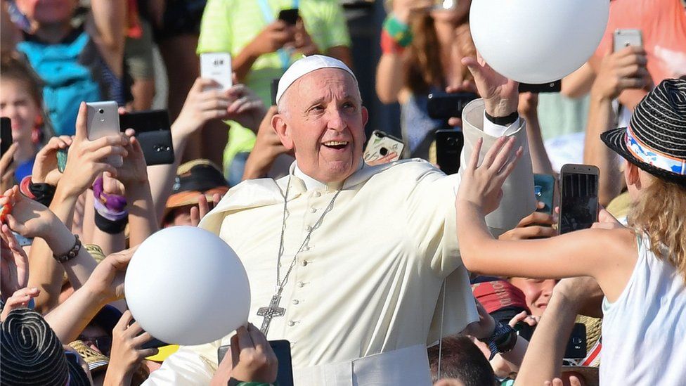 Pope Francis plays with a balloon as he meets a crowd of people