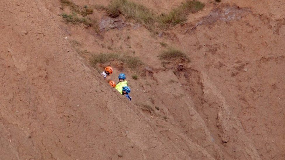 Coastguard crew rescuing a man and a woman from Filey Brigg in North Yorkshire