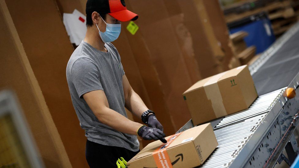 A worker moves boxes of goods to be scanned and sent to delivery trucks during operations at Amazon"s Robbinsville fulfillment center in Robbinsville, New Jersey, U.S., November 29, 2021.