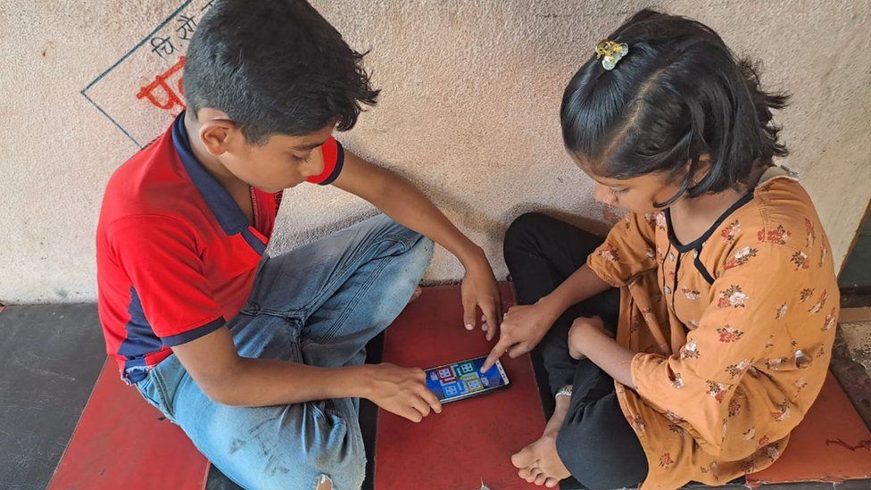 Двое детей играют на мобильном телефоне