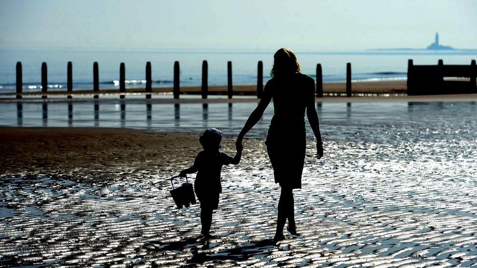 Woman and child walking on the beach at Blyth