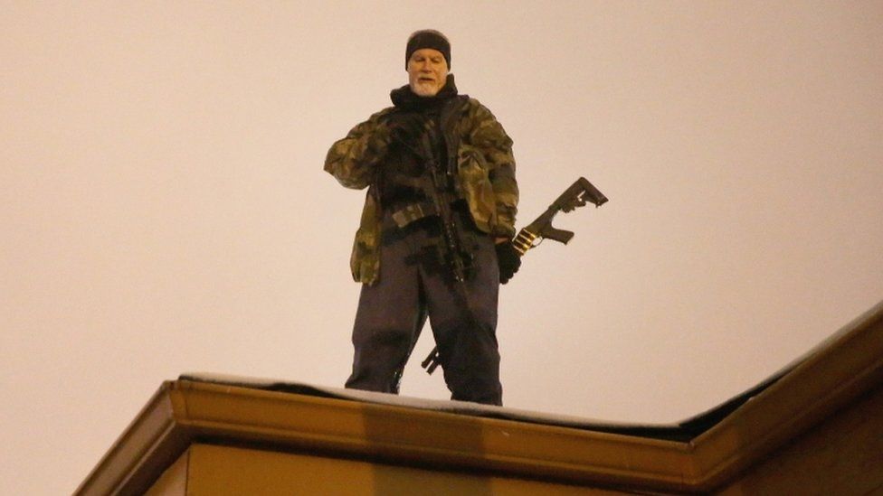 John Karriman. a volunteer from Oath Keepers, stands guard on the rooftop of a business on 26 November 2014 in Ferguson, Missouri.