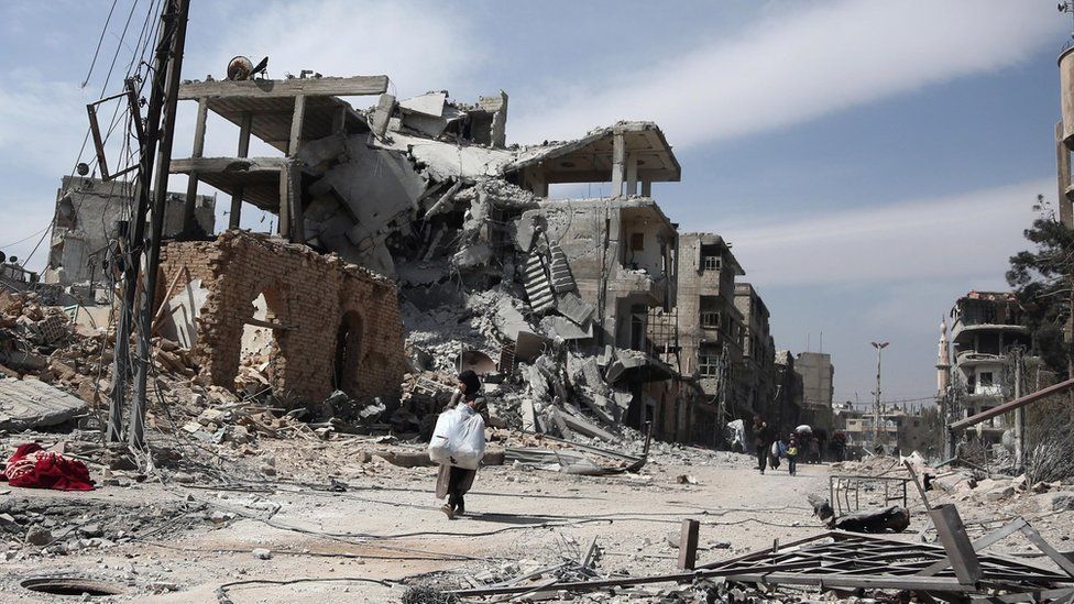 People carry their belongings as they leave the town of Hamouria in the Eastern Ghouta (15 March 2018)