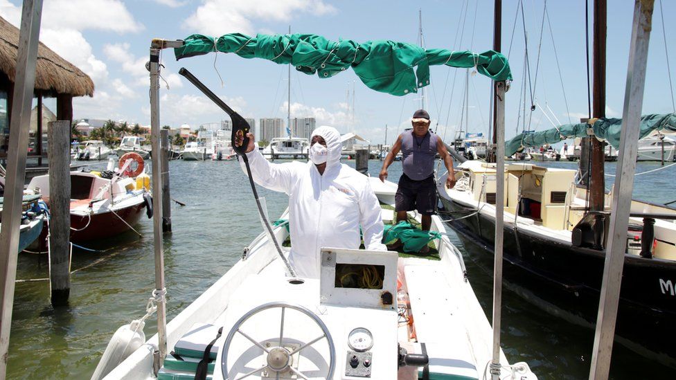 An employee of a private company disinfects a boat at a marina in Cancun