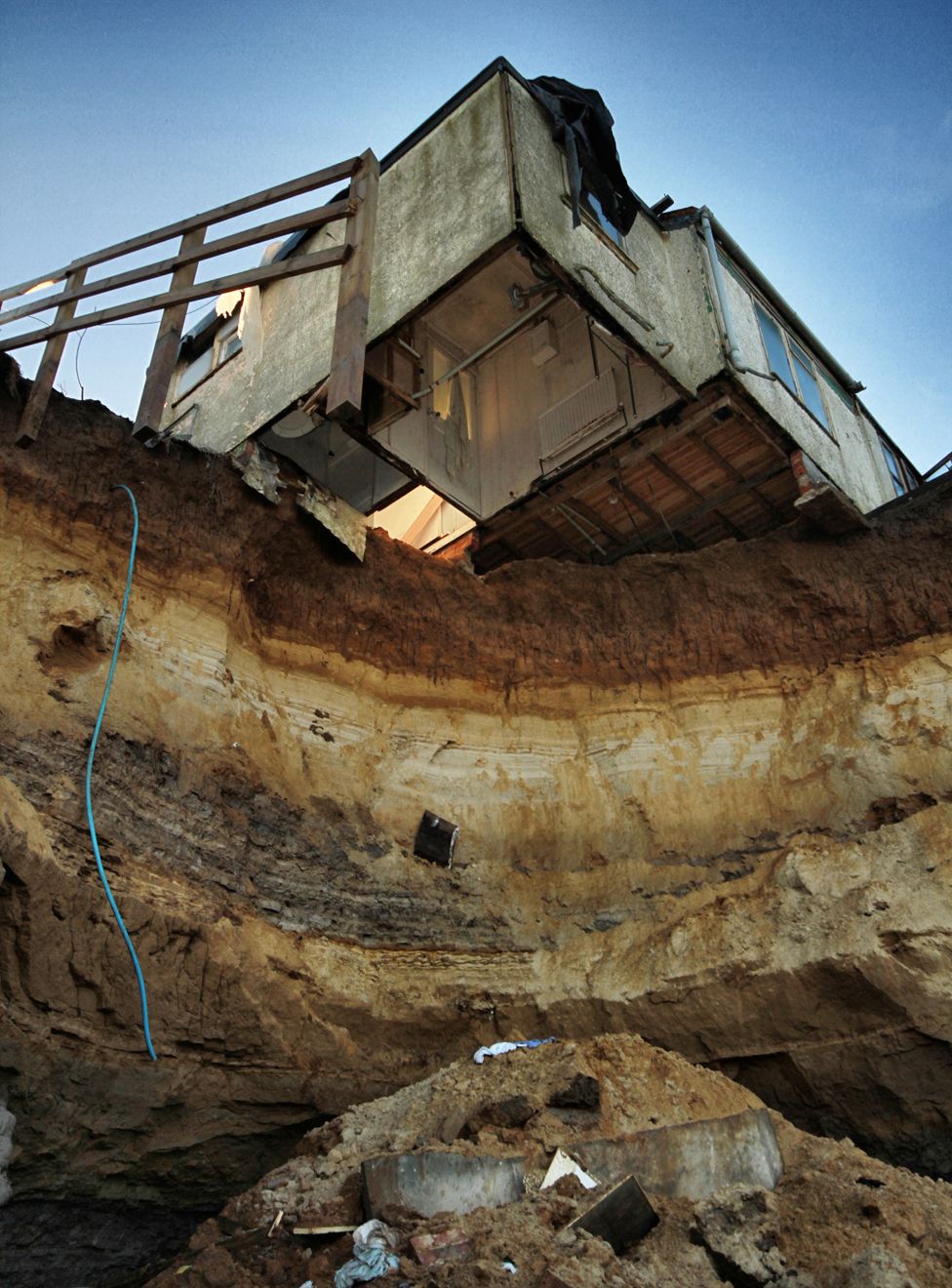 View looking upwards from the beach to the house overhanging the cliff edge