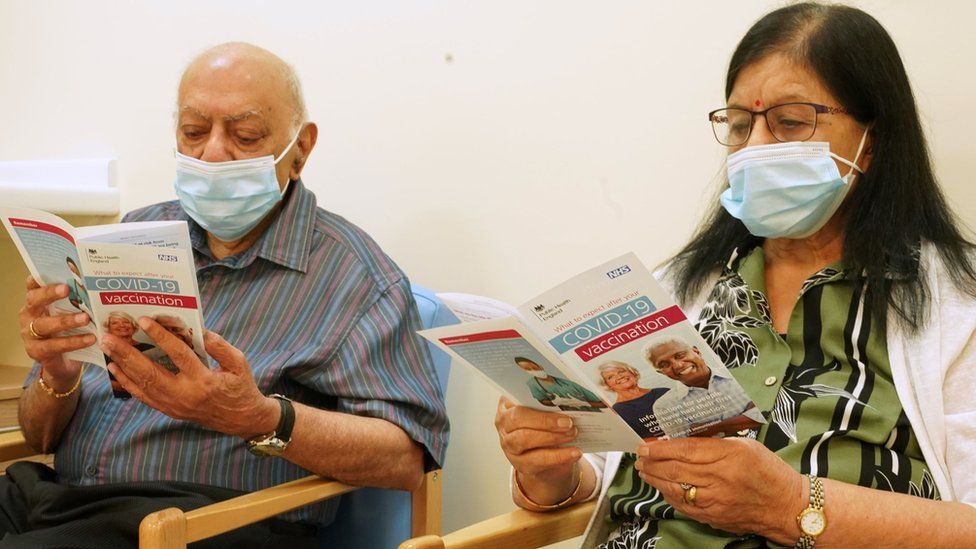 A South Asian couple reading Covid vaccine leaflets