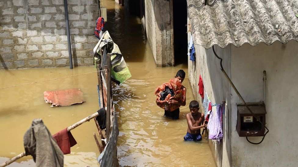 Sri Lankan youths wade through floodwaters