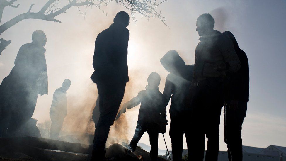 Refugees stand near a makeshift fire as they wait to be allowed to cross the border to Macedonia in the northern Greek border station of Idomeni, on Wednesday, 2 March 2016