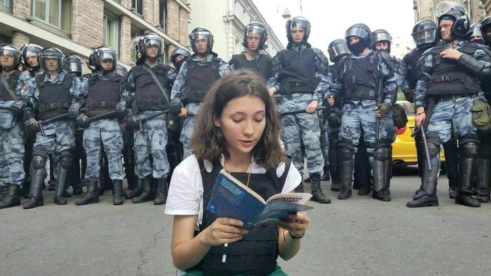 Olga Misik reads constitution as dozens of riot police stand behind her