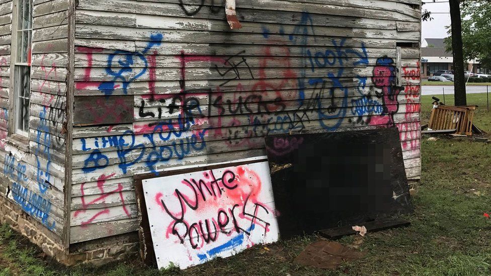 Graffiti covers one side of the historical Ashburn old school - signs read "white power" "life sucks" and there are several swastikas.